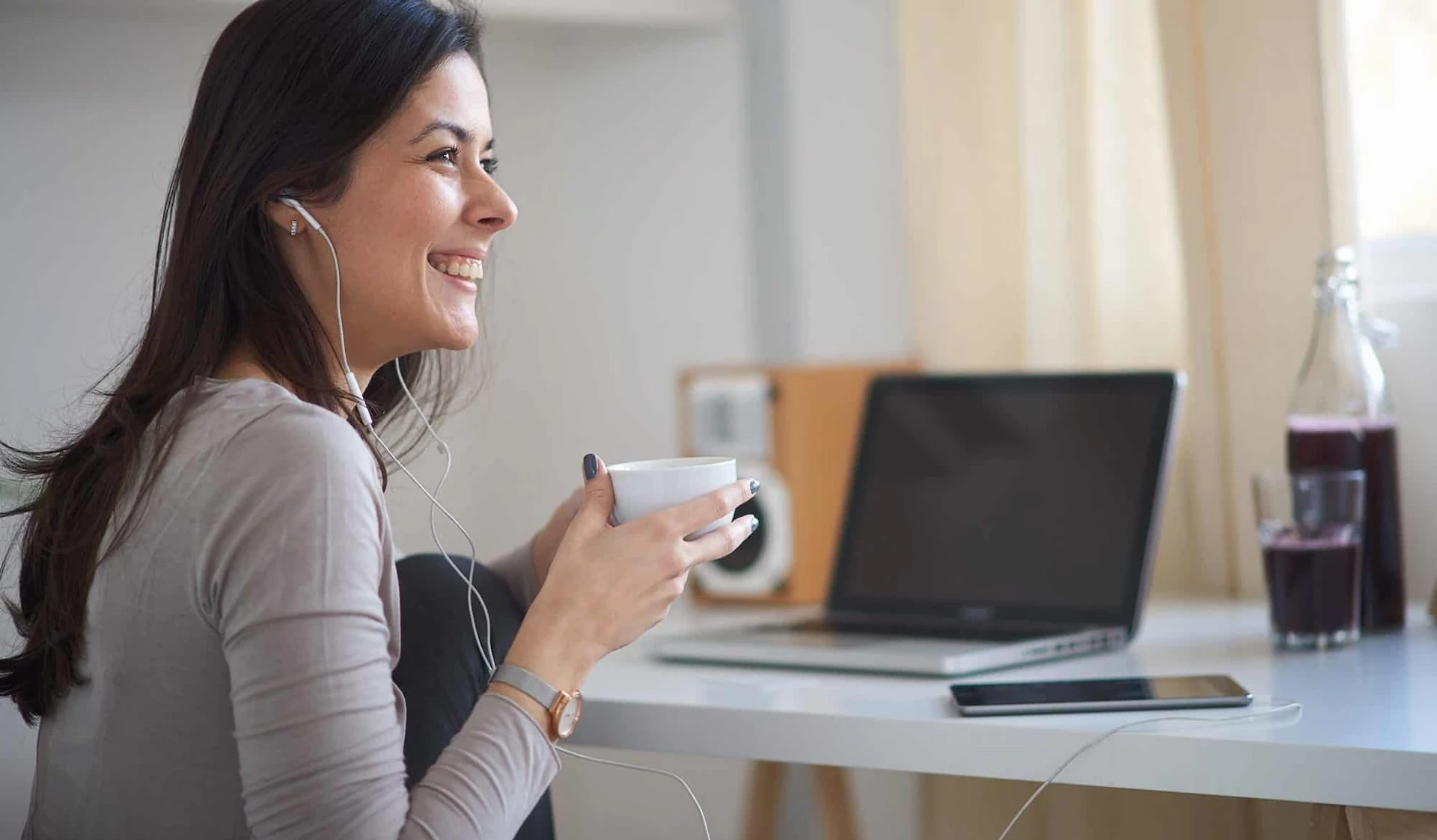 woman smiling with ear buds at a desk