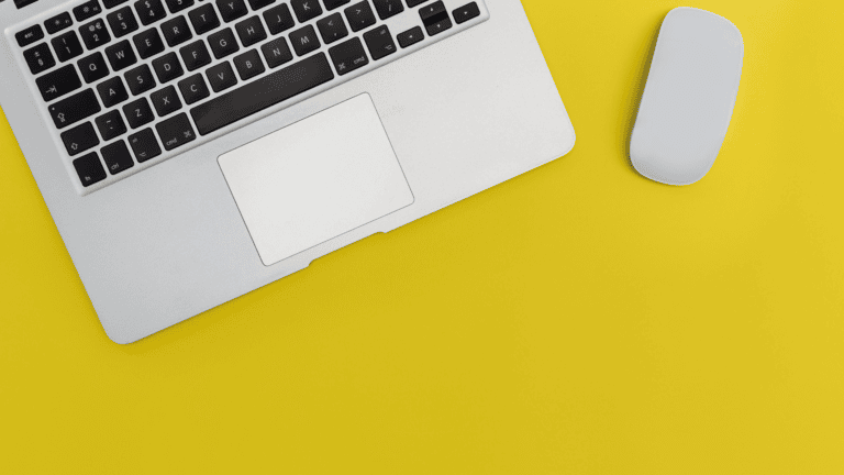 top view of a laptop and mouse on a yellow background