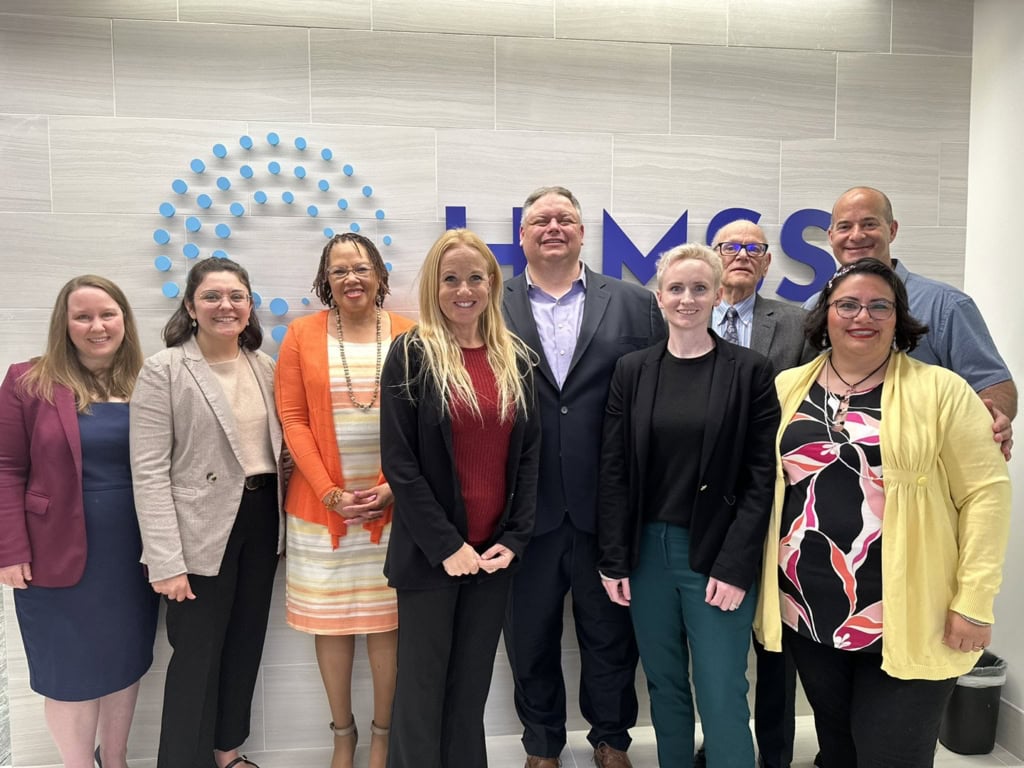 Group of professionals posing in front of a company logo