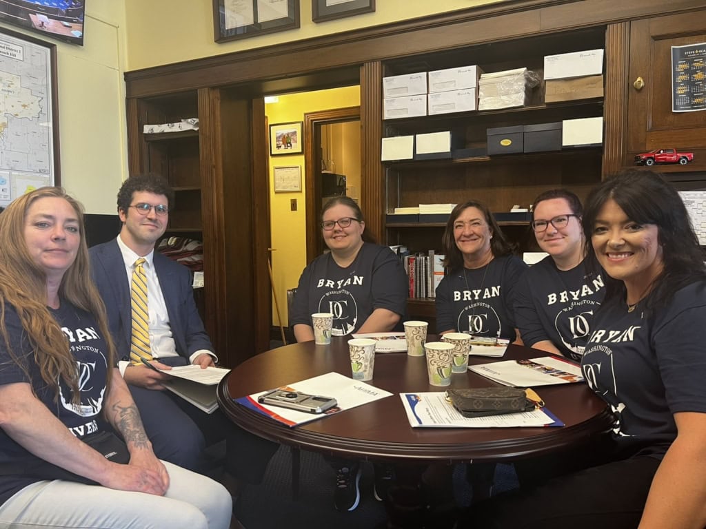 A group of Bryan University students sits at a table with an official in Washinton, DC