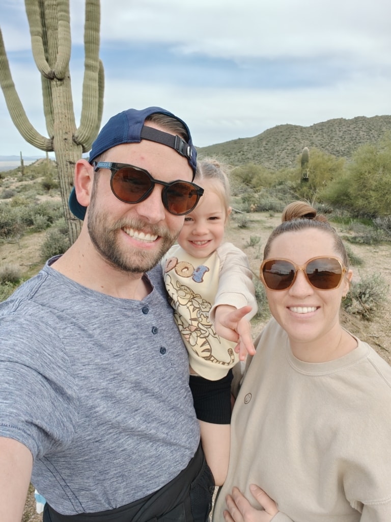 A picture of a smiling man holding a toddler next to a smiling woman