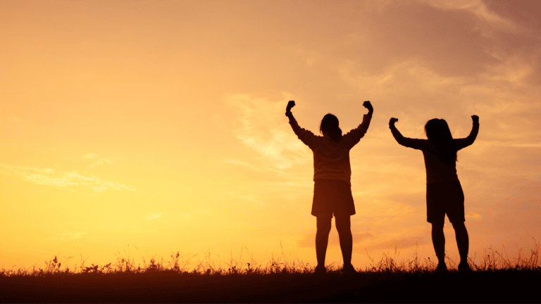 Two people standing in front of a sunset