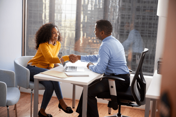 student shaking hands with advisor at desk