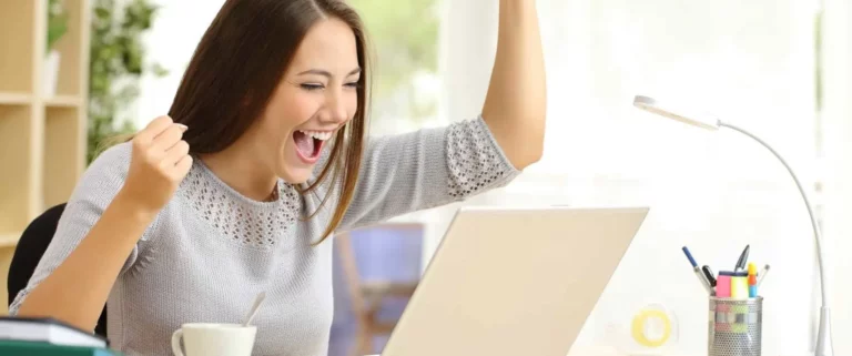 Young woman celebrating at computer|Graduation